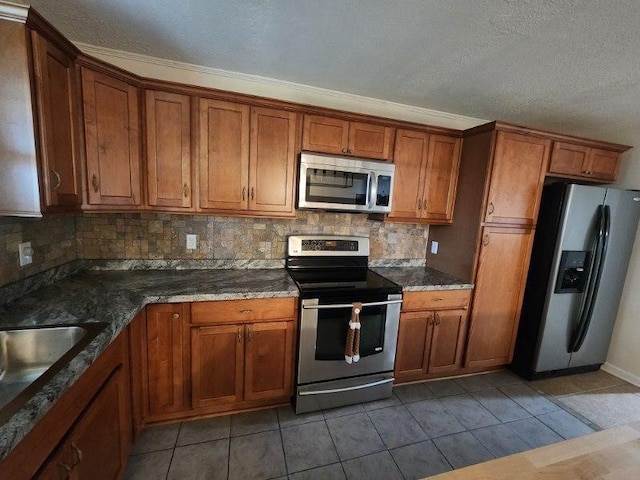 kitchen featuring stainless steel appliances, dark tile patterned floors, sink, backsplash, and dark stone counters