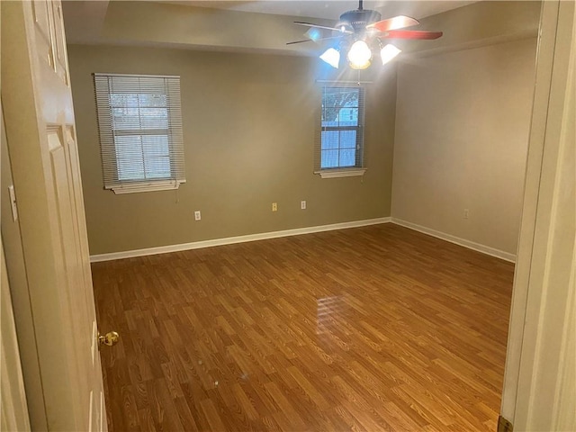 empty room with ceiling fan, a wealth of natural light, and wood-type flooring