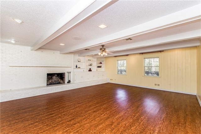 unfurnished living room with dark hardwood / wood-style flooring, a brick fireplace, beam ceiling, and a textured ceiling