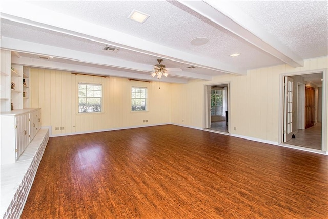 unfurnished room with ceiling fan, wood-type flooring, a textured ceiling, beamed ceiling, and wood walls