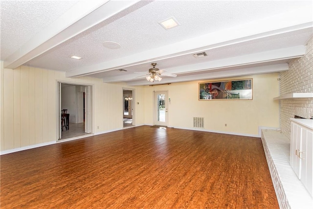 unfurnished living room with hardwood / wood-style flooring, beam ceiling, ceiling fan, a brick fireplace, and a textured ceiling