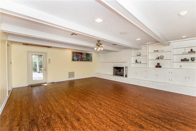 unfurnished living room featuring a brick fireplace, beam ceiling, a textured ceiling, and ceiling fan