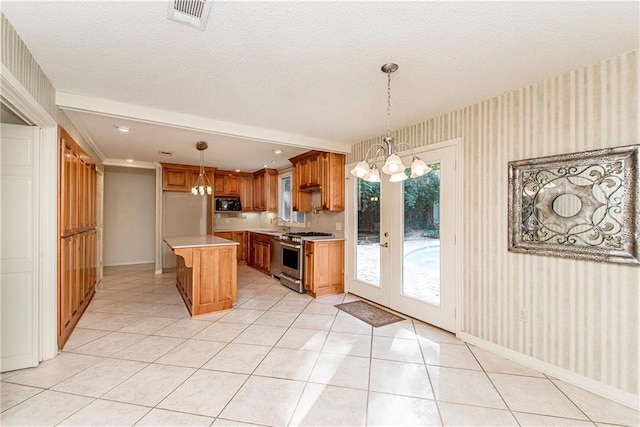 kitchen featuring a center island, stainless steel gas range, a chandelier, and decorative light fixtures