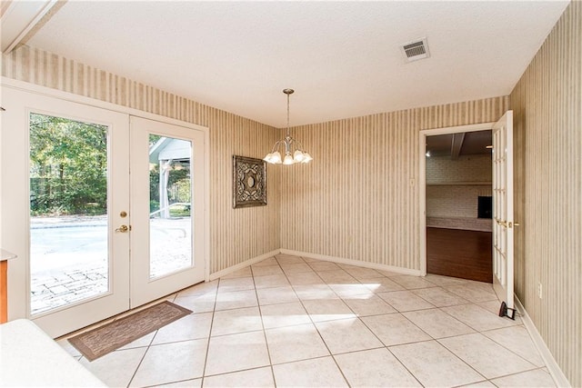 unfurnished dining area featuring tile patterned flooring, a notable chandelier, and french doors