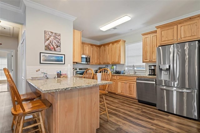 kitchen with dark wood-type flooring, a breakfast bar, ornamental molding, appliances with stainless steel finishes, and light stone countertops