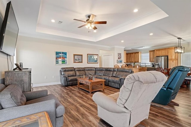 living room featuring ornamental molding, dark hardwood / wood-style flooring, and a tray ceiling