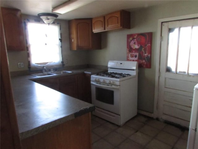 kitchen featuring sink, white range with gas stovetop, and light tile flooring