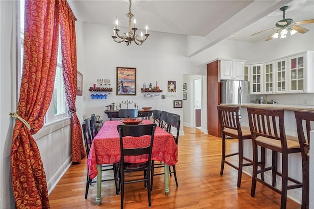 dining room with ceiling fan with notable chandelier and light hardwood / wood-style flooring