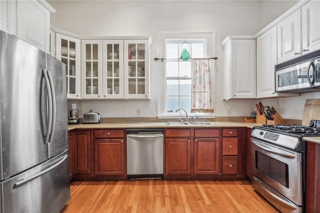 kitchen featuring white cabinetry, appliances with stainless steel finishes, sink, and light wood-type flooring