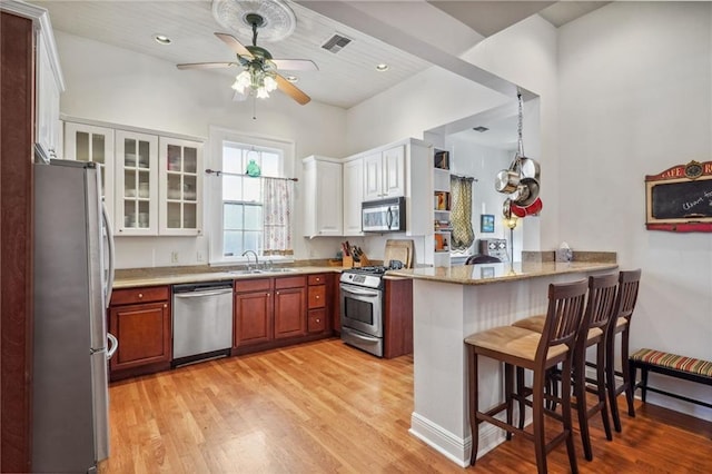 kitchen featuring appliances with stainless steel finishes, white cabinetry, a kitchen breakfast bar, light hardwood / wood-style floors, and kitchen peninsula