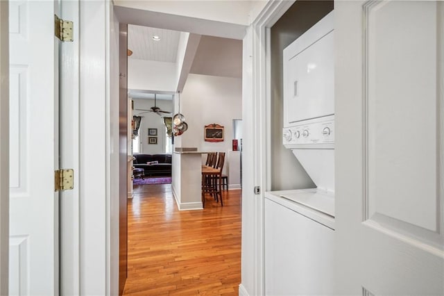 laundry room with stacked washer / drying machine, hardwood / wood-style floors, and ceiling fan