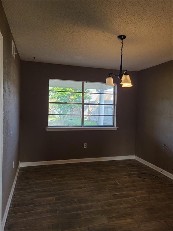 unfurnished room featuring dark hardwood / wood-style flooring, a chandelier, and a textured ceiling