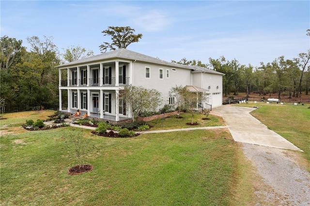 rear view of property with a garage, a balcony, and a lawn