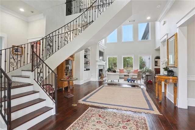 foyer with dark hardwood / wood-style floors, a towering ceiling, and crown molding