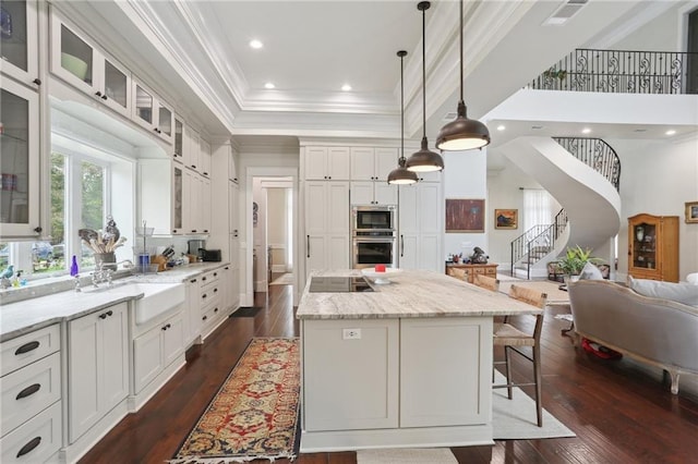 kitchen with appliances with stainless steel finishes, a kitchen island with sink, white cabinets, dark hardwood / wood-style floors, and a kitchen breakfast bar