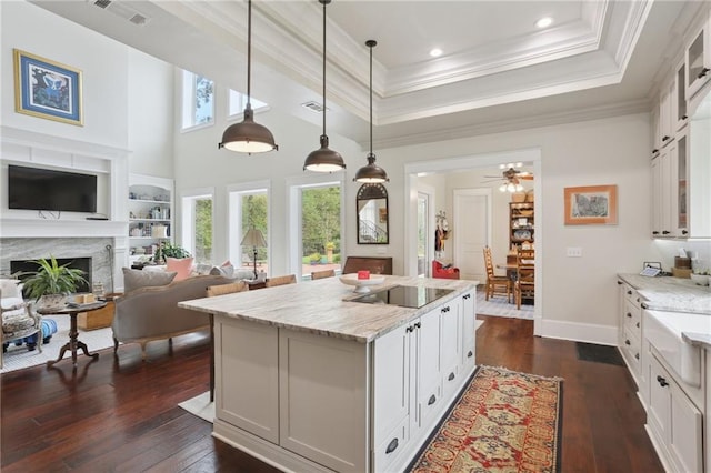 kitchen with decorative light fixtures, white cabinets, dark hardwood / wood-style floors, a high end fireplace, and ceiling fan