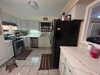 kitchen with appliances with stainless steel finishes, light tile patterned floors, and white cabinets