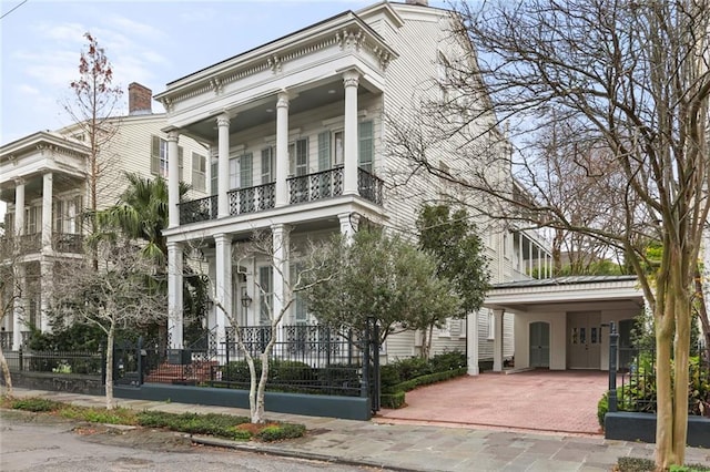 neoclassical home featuring a balcony and a carport