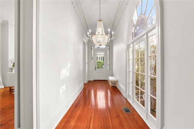 doorway to outside featuring crown molding, dark hardwood / wood-style floors, and a chandelier