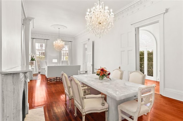 dining area with a fireplace, crown molding, an inviting chandelier, and dark hardwood / wood-style flooring