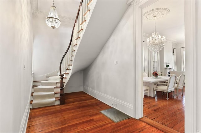 staircase featuring a chandelier, crown molding, and dark wood-type flooring