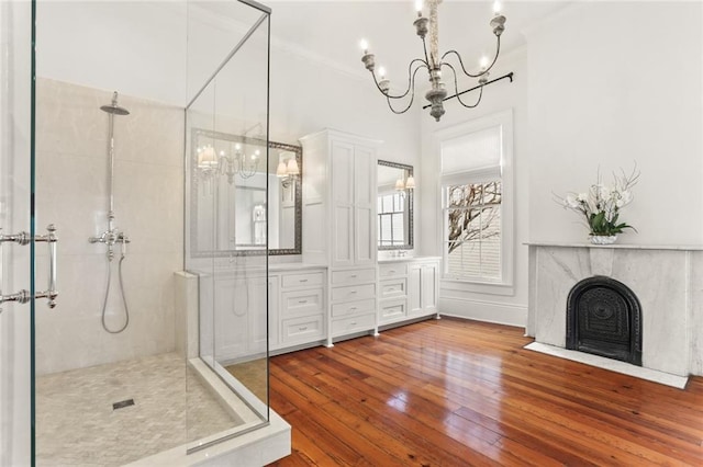 bathroom featuring hardwood / wood-style floors, vanity, a premium fireplace, a shower with door, and a chandelier