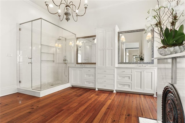 bathroom with wood-type flooring, a shower with shower door, vanity, and a notable chandelier