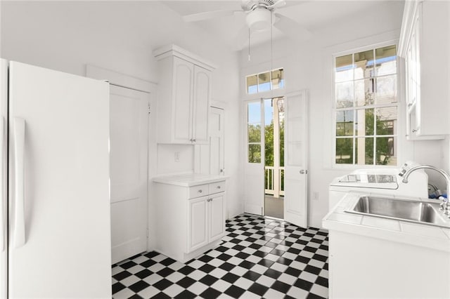 kitchen featuring white fridge, ceiling fan, sink, dark tile floors, and white cabinets