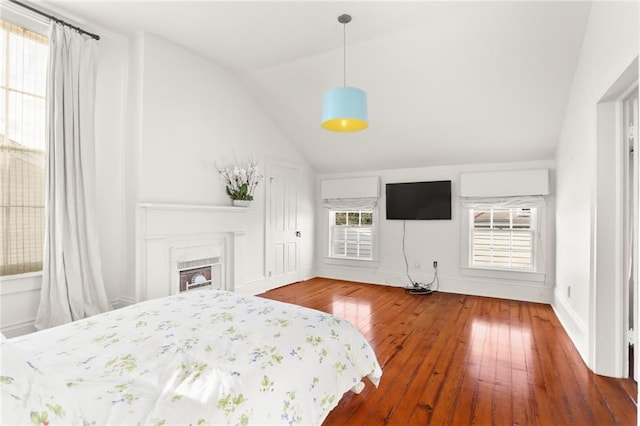 unfurnished bedroom with hardwood / wood-style floors, vaulted ceiling, and multiple windows