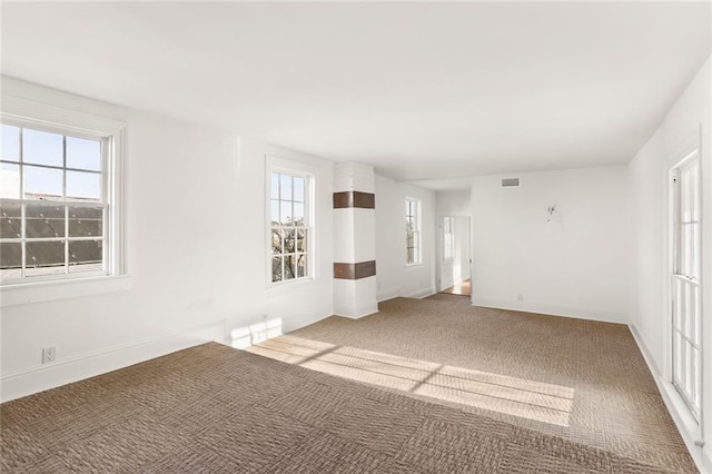 spare room with dark colored carpet and plenty of natural light