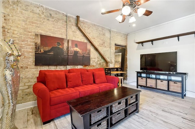 living room with brick wall, ceiling fan, and light hardwood / wood-style flooring