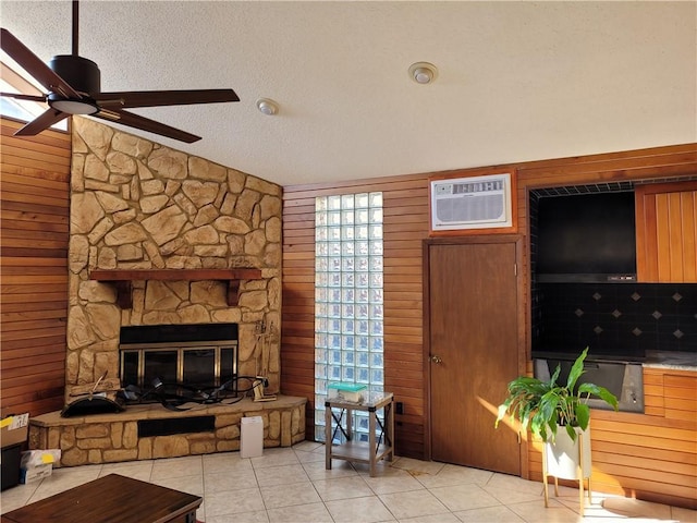 living room featuring a textured ceiling, a fireplace, ceiling fan, and light tile floors
