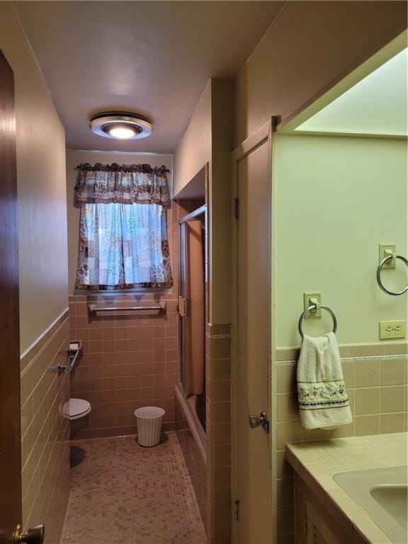 bathroom featuring tile walls, toilet, a shower with door, tile floors, and vanity