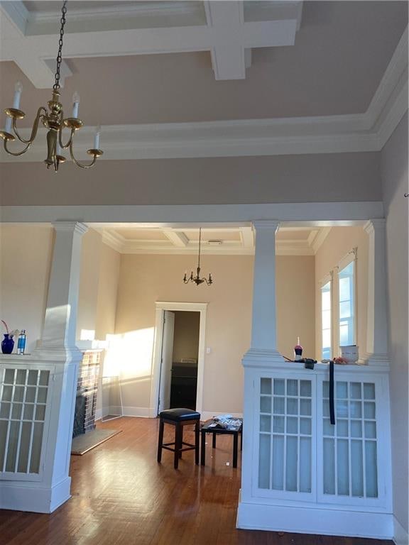 interior space with dark hardwood / wood-style floors, coffered ceiling, ornamental molding, and a chandelier