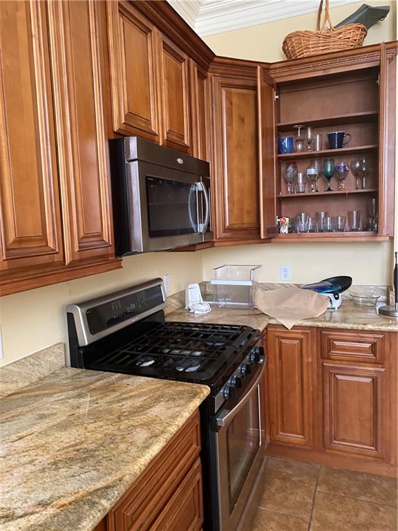 161214 N Broad St, New Orleans, LA 70119 - kitchen featuring appliances with stainless steel finishes, ornamental molding, light stone counters, and light tile floors