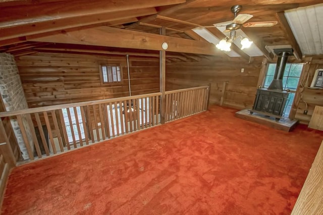 interior space featuring ceiling fan, vaulted ceiling with beams, carpet flooring, and a wood stove