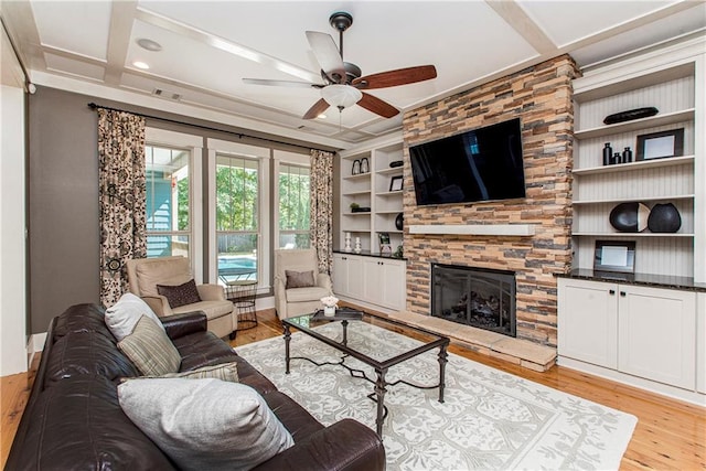 living room featuring ceiling fan, built in features, a fireplace, and light hardwood / wood-style floors