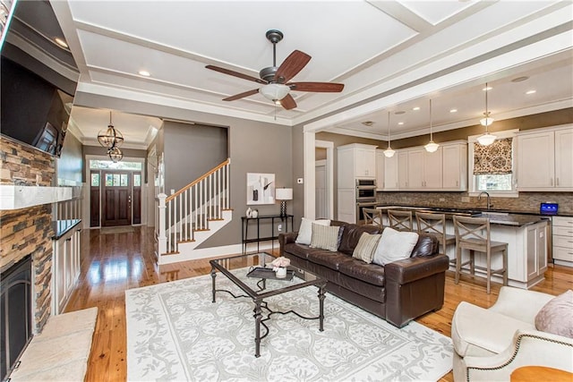 living room with crown molding, ceiling fan, light hardwood / wood-style flooring, and a fireplace