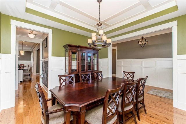 dining area featuring an inviting chandelier, a tray ceiling, and light wood-type flooring