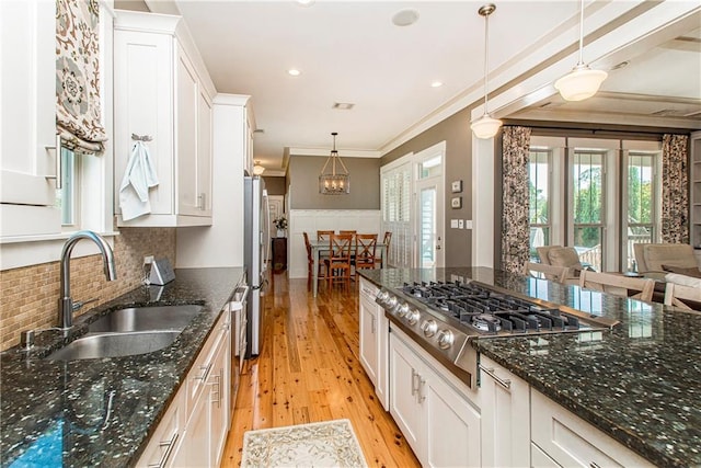 kitchen with dark stone countertops, ornamental molding, decorative light fixtures, and light hardwood / wood-style flooring