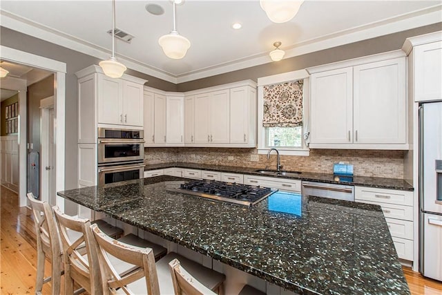 kitchen with white cabinets, dark stone countertops, stainless steel appliances, and light wood-type flooring