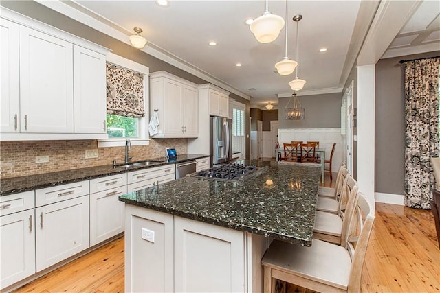 kitchen with a breakfast bar area, light hardwood / wood-style floors, dark stone counters, and a center island