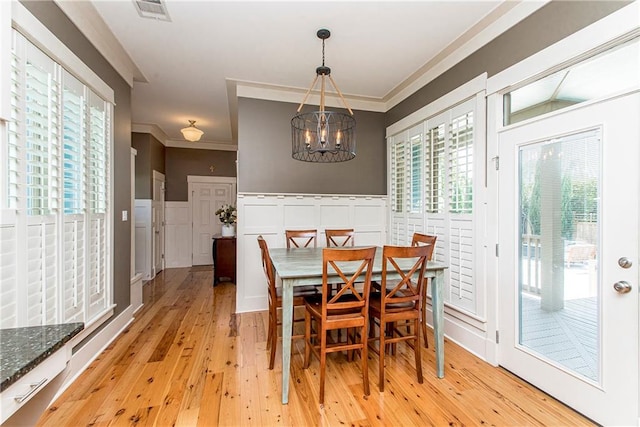 dining space featuring an inviting chandelier, crown molding, and light wood-type flooring