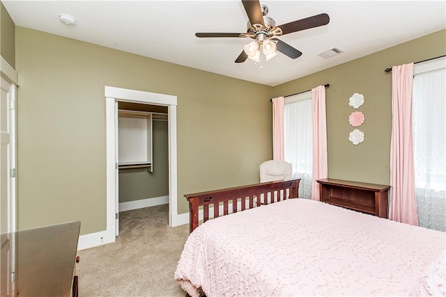 bedroom with ceiling fan, multiple windows, light carpet, and a closet