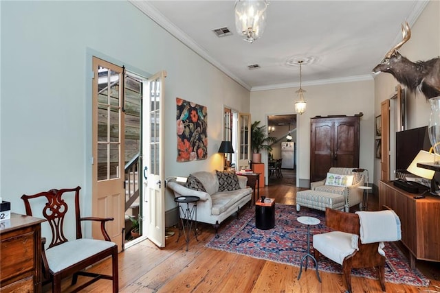 living room with ornamental molding, wood-type flooring, and a notable chandelier