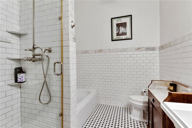 bathroom with tile walls, toilet, vanity, and tile flooring