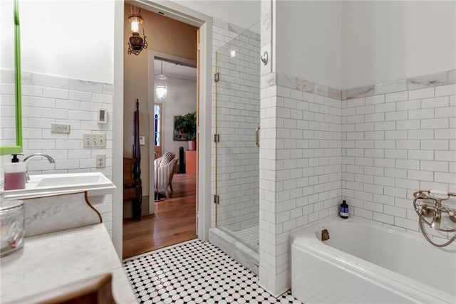 bathroom featuring tile flooring, independent shower and bath, sink, and tile walls