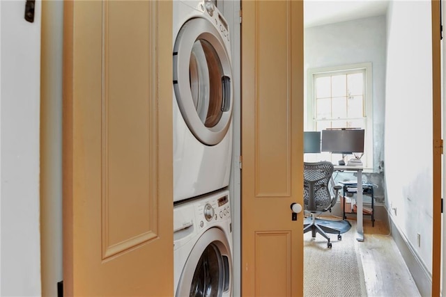 laundry room with stacked washer and dryer and light wood-type flooring