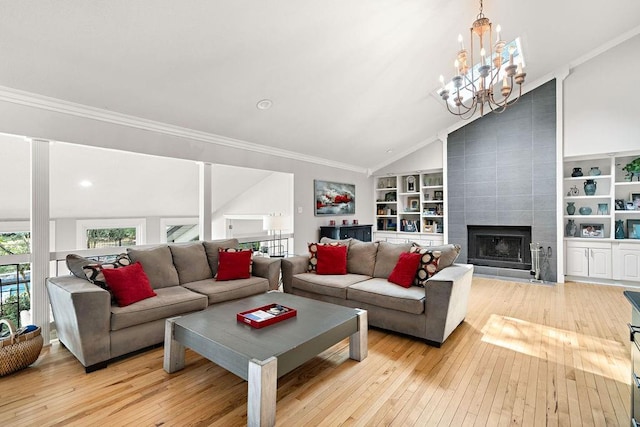 living room with a tiled fireplace, light wood-type flooring, crown molding, and a notable chandelier