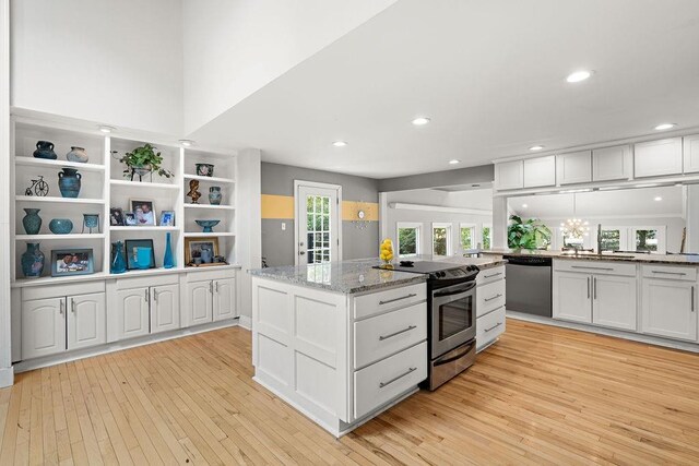 kitchen with appliances with stainless steel finishes, light hardwood / wood-style flooring, light stone counters, white cabinetry, and a chandelier